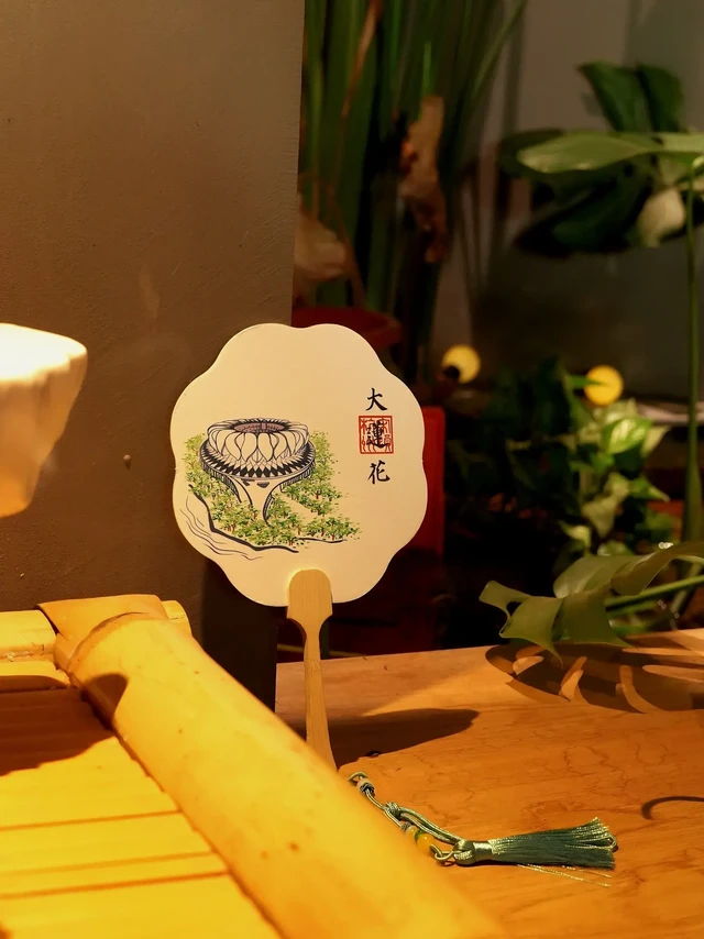 大莲花团扇.西泠印社现场印章。这一柄团扇，承古意之形，载今朝之景。
扇面绘杭州地标“大莲花”，一彩一墨，两幅画卷，皆蕴江南气韵。
泼墨山水隐于现代线条之中，莲瓣如城，城如画卷。

🪷西泠印社设计出品，