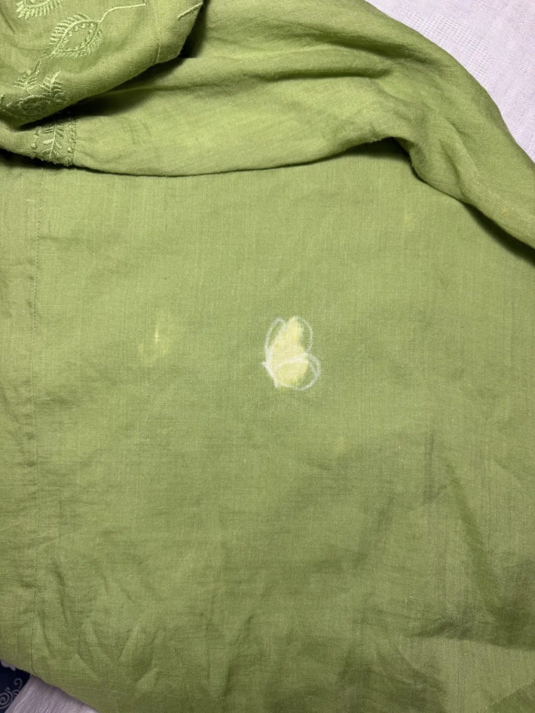 绣补师在待补衣物的污渍破洞处用粉笔起稿花样