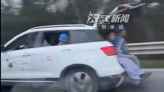 车辆后备箱打开坐着两人 车辆行驶在国道上 当地回应：正在核查