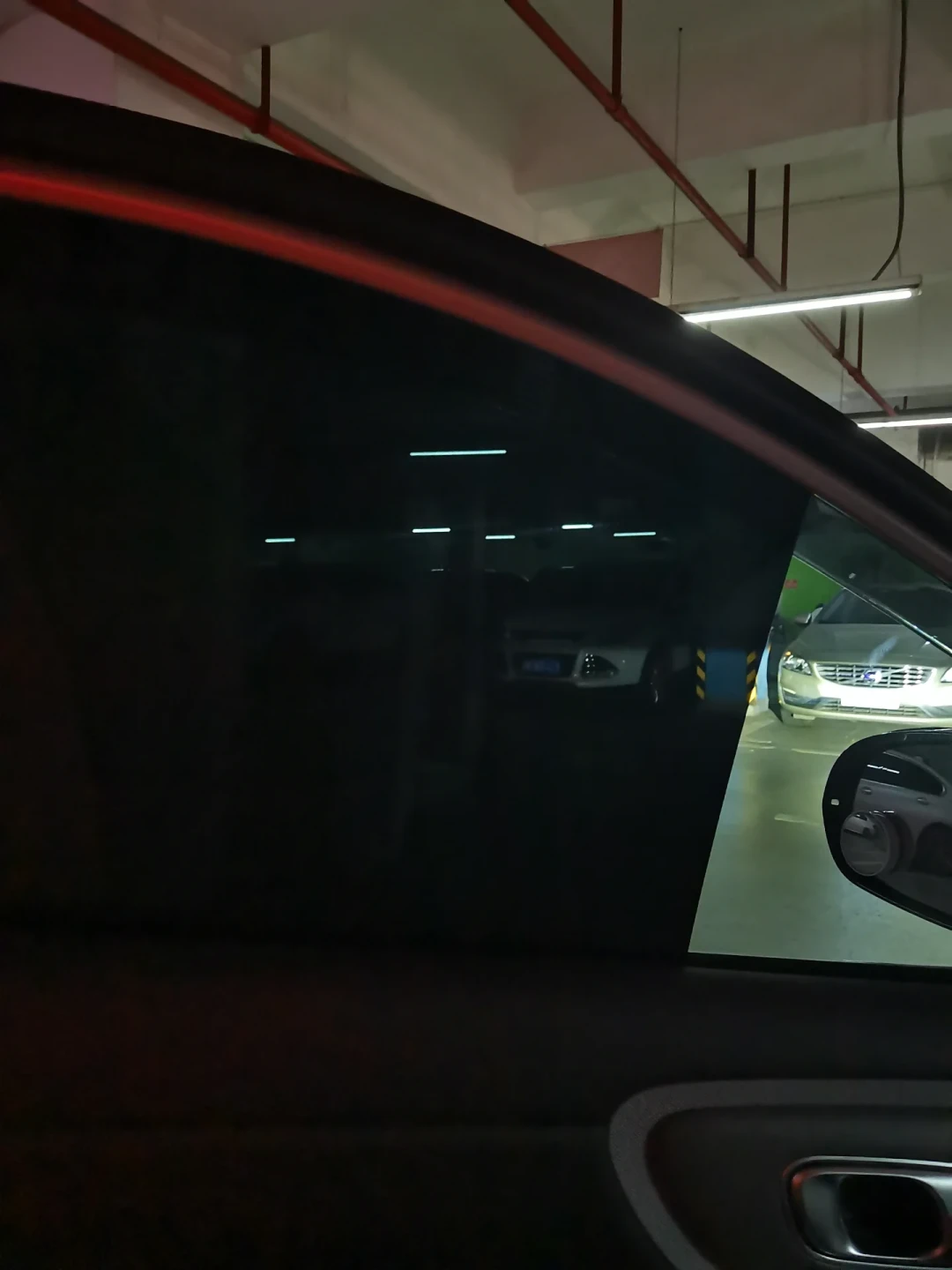 夜间地库中贴了赠送膜的车窗从车内几乎全黑，与未贴膜三角窗形成对比