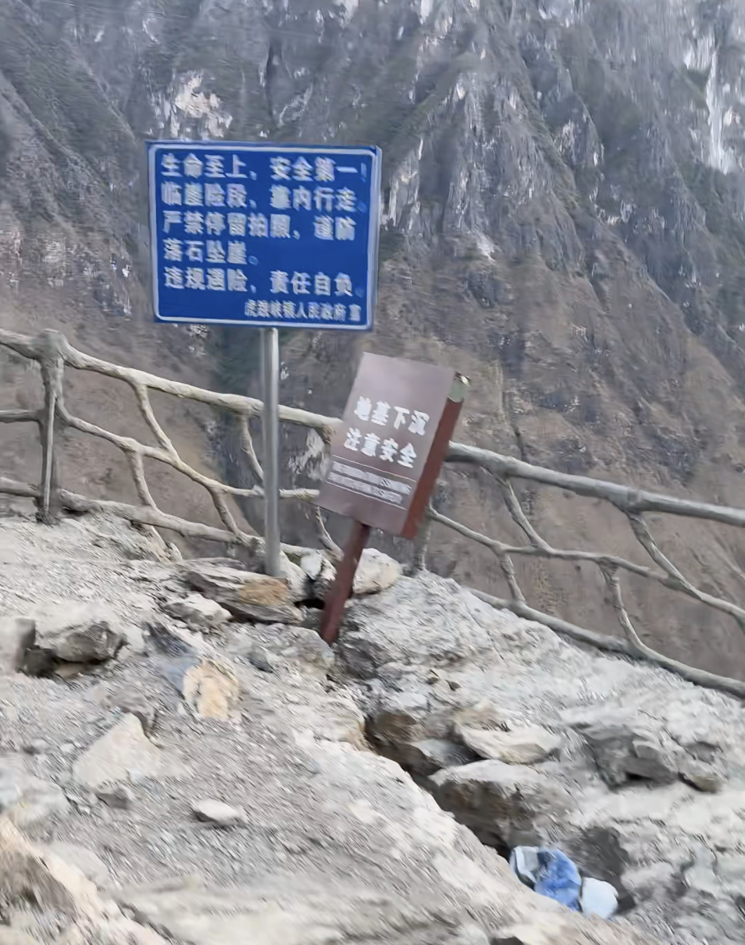 崖边警示牌与已装仿木护栏